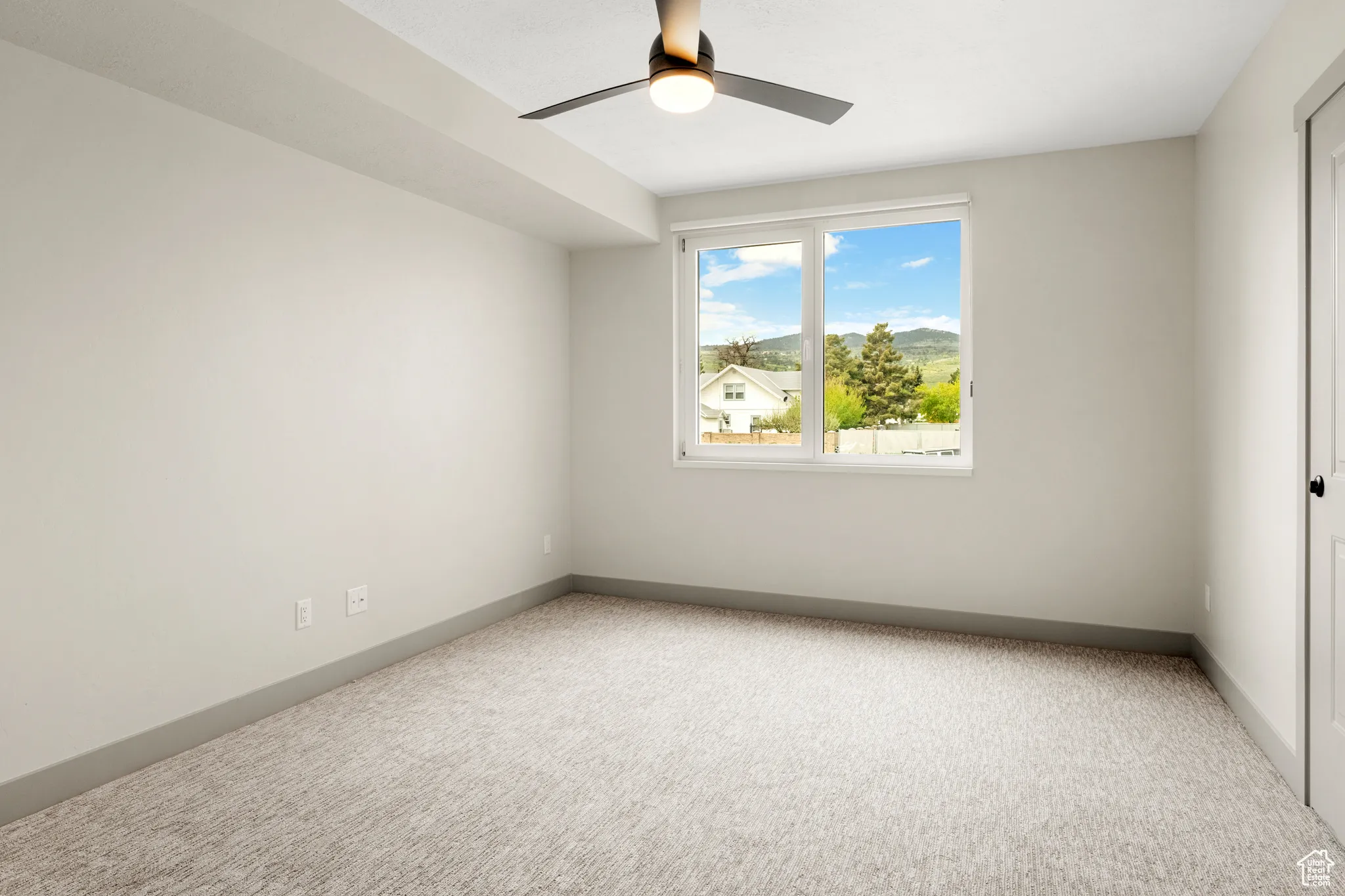 Carpeted spare room featuring a ceiling fan and baseboards