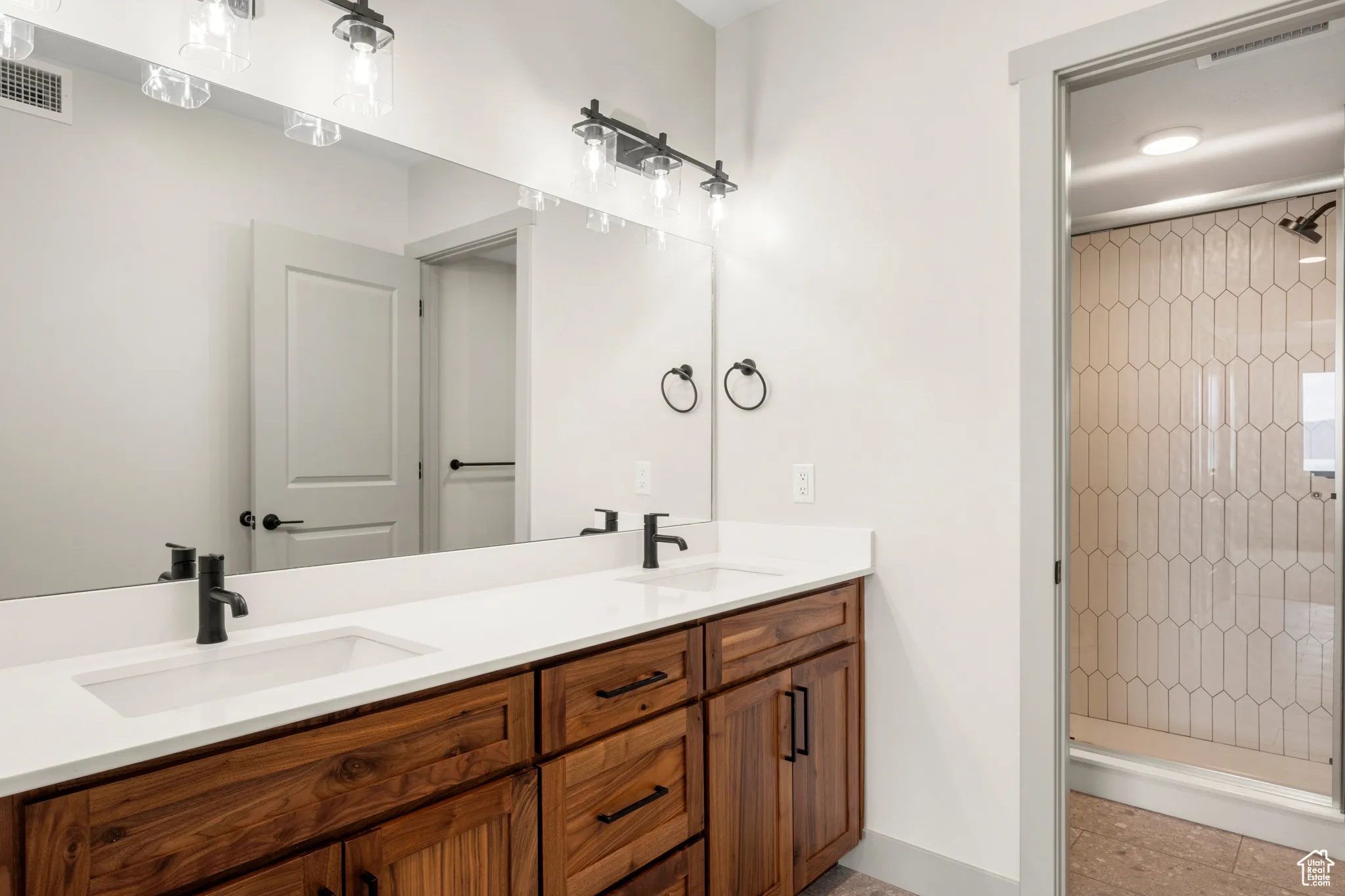 Bathroom with a stall shower, double vanity, and baseboards