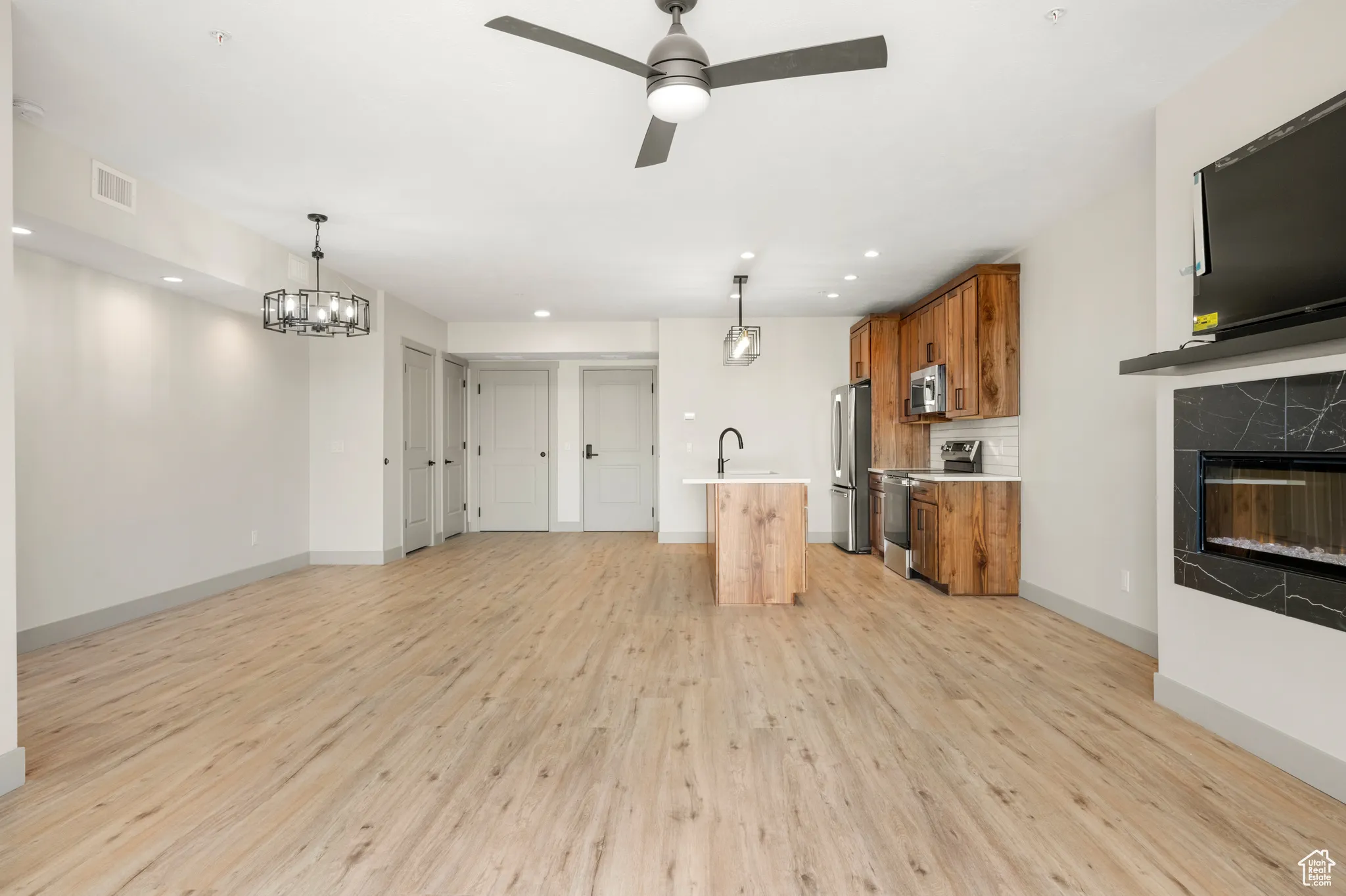 Unfurnished living room featuring light wood-type flooring, a ceiling fan, baseboards, a high end fireplace, and recessed lighting