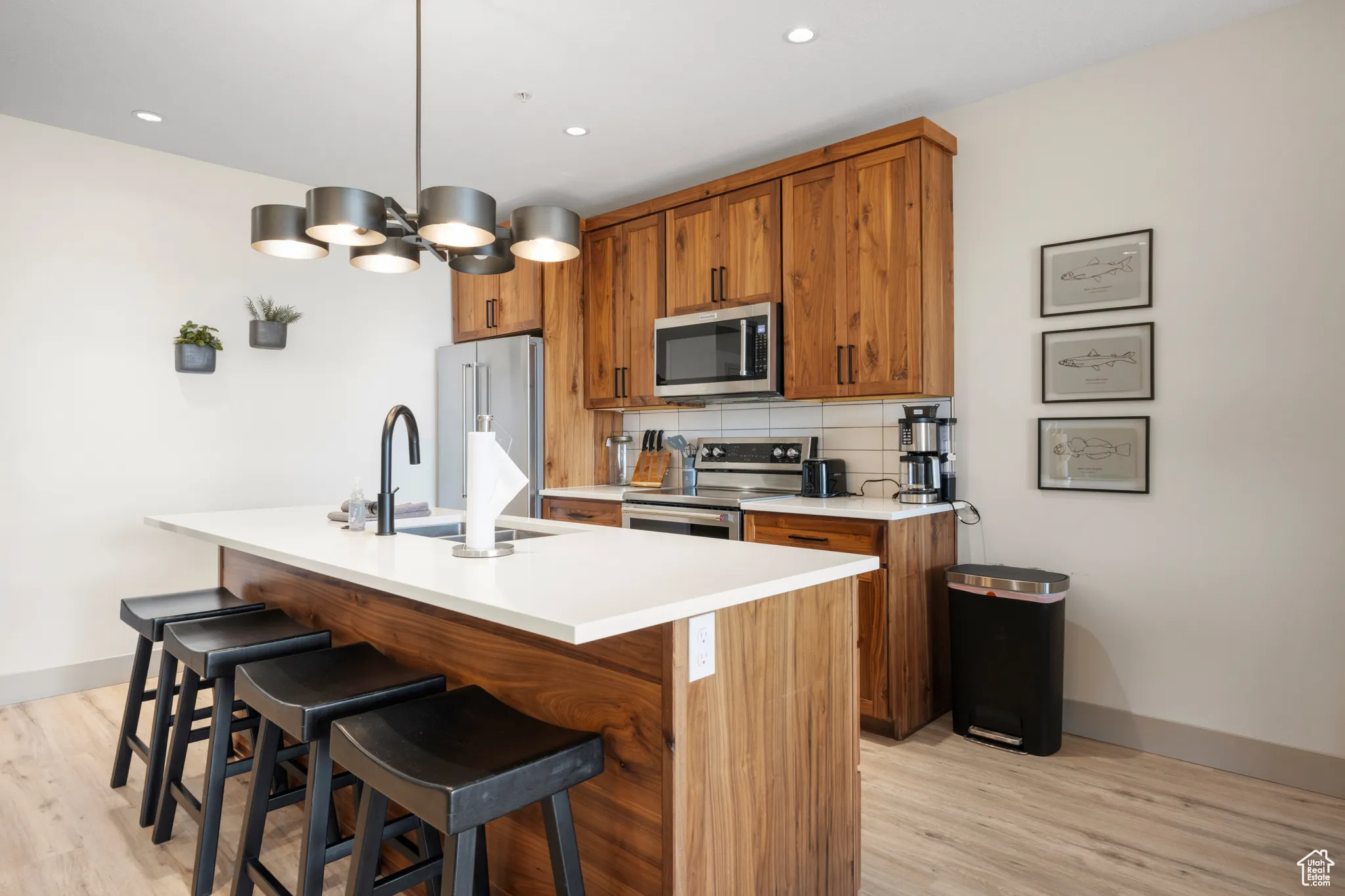Kitchen featuring appliances with stainless steel finishes, brown cabinets, light wood finished floors, and recessed lighting