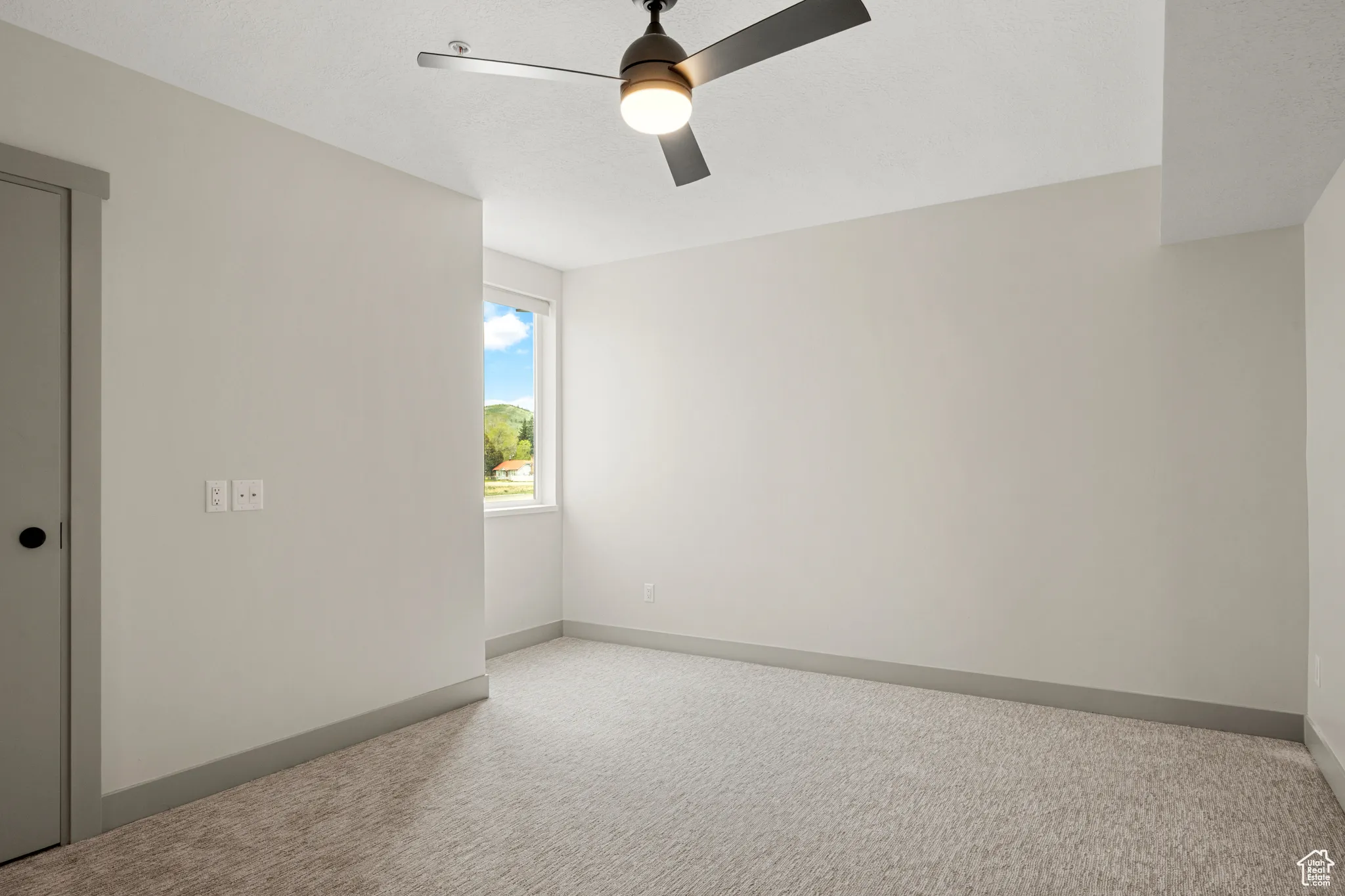 Carpeted empty room with a ceiling fan and baseboards