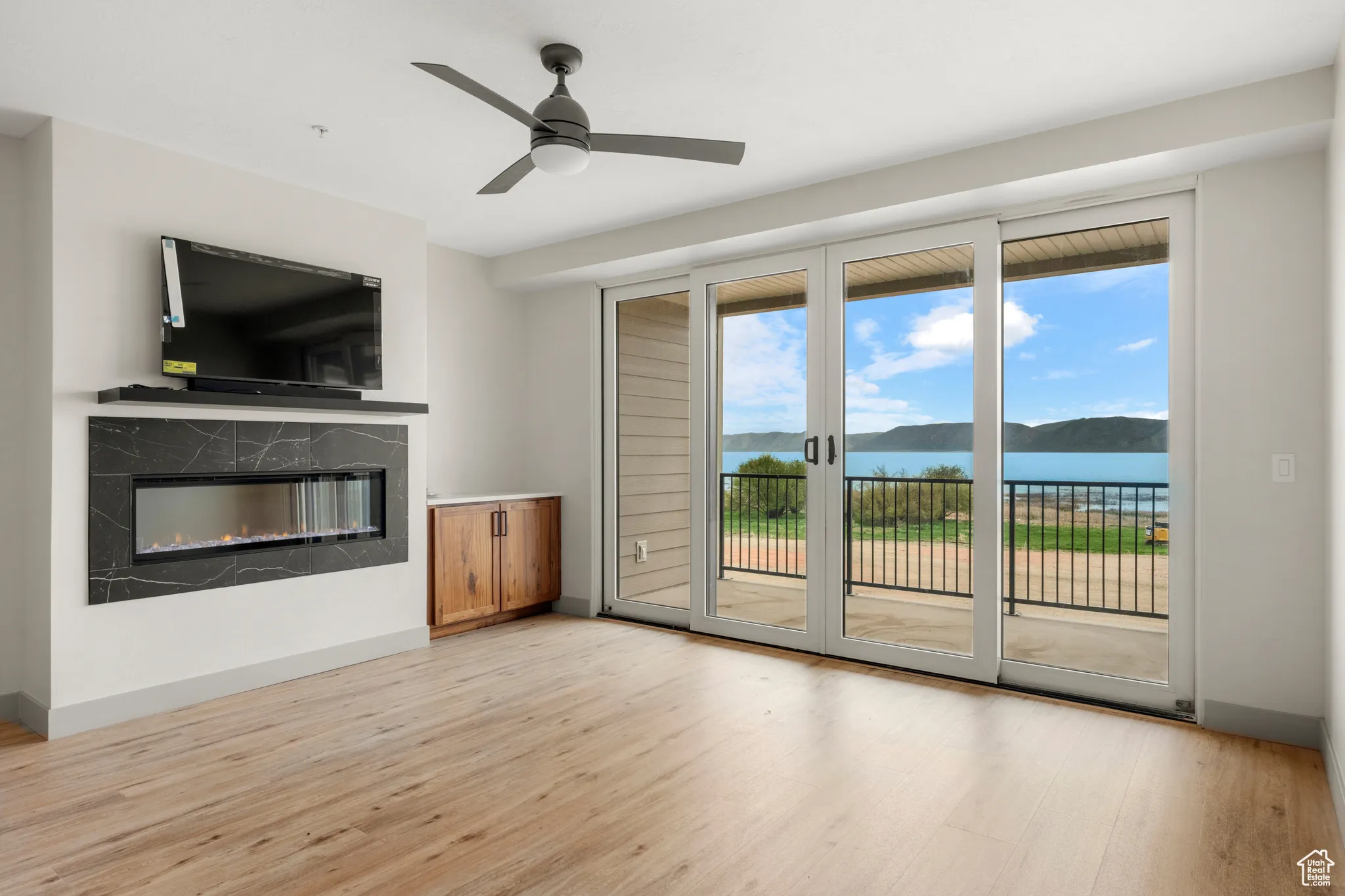 Unfurnished living room featuring light wood-style floors, a premium fireplace, ceiling fan, and baseboards