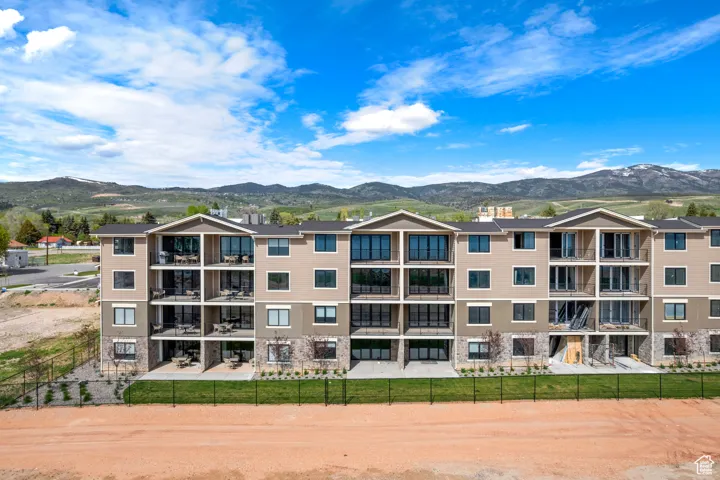 View of apartment building / complex featuring a mountain view and fence