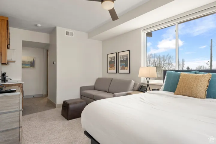 Bedroom featuring light carpet, ceiling fan, and baseboards