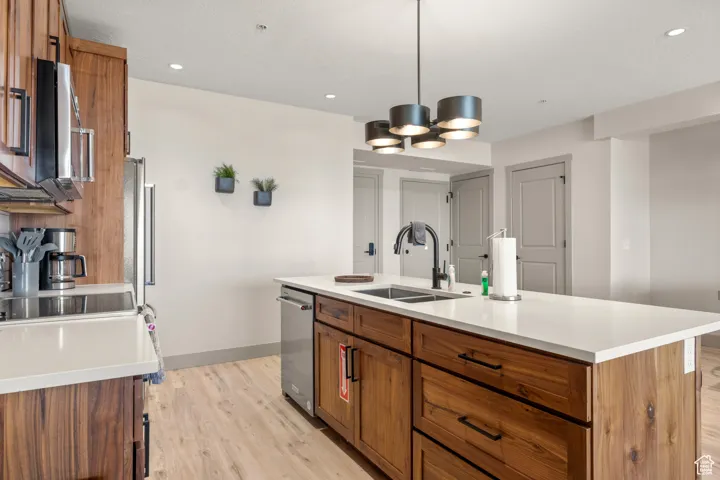Kitchen featuring a sink, brown cabinets, light wood-type flooring, baseboards, and light countertops