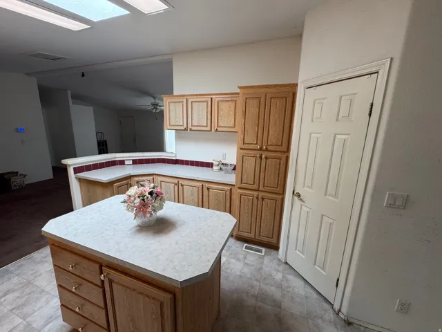Kitchen featuring a peninsula, light countertops, a kitchen island, and light wood finish cabinets