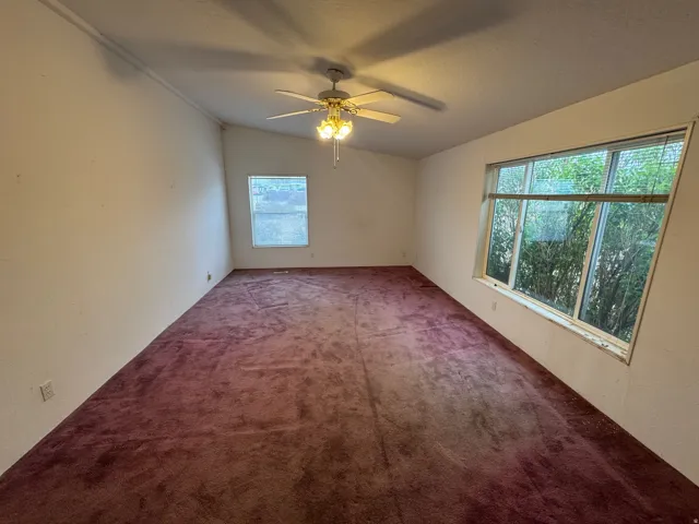 Carpeted empty room featuring a ceiling fan