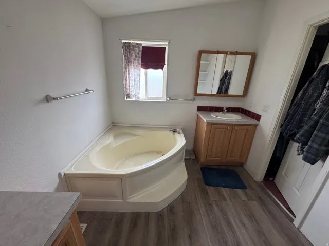 Bathroom with vanity, a bath, and dark wood-type flooring