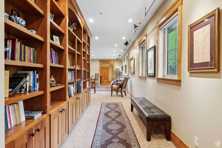 Hallway with arched walkways, light colored carpet, recessed lighting, and baseboards