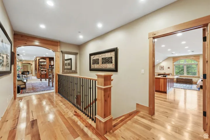 Hallway featuring arched walkways, hardwood / wood-style floors, recessed lighting, an upstairs landing, and baseboards