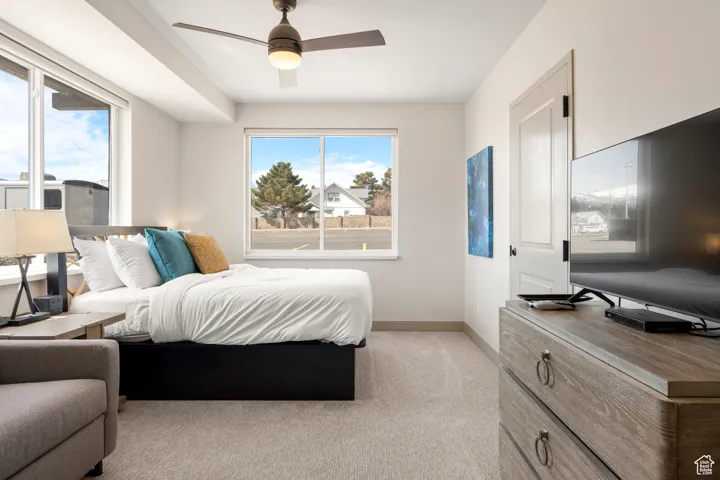 Bedroom with baseboards, light colored carpet, and a ceiling fan