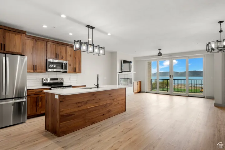 Kitchen with stainless steel appliances, a sink, open floor plan, decorative backsplash, and recessed lighting