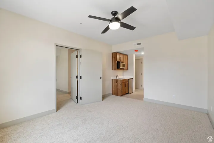 Unfurnished bedroom with light carpet and ceiling fan