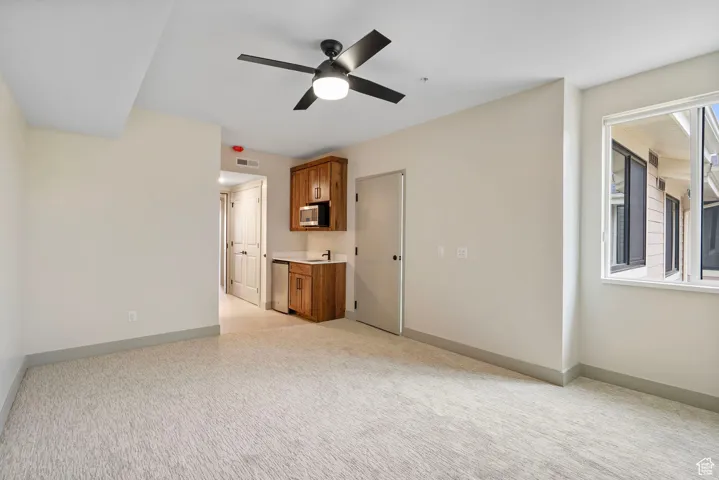 Unfurnished living room featuring light colored carpet and a ceiling fan