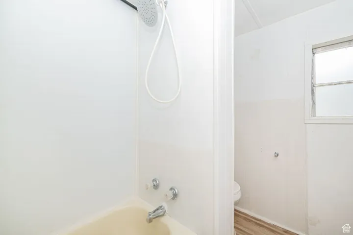 Full bathroom featuring toilet, wood finished floors, and tub / shower combination