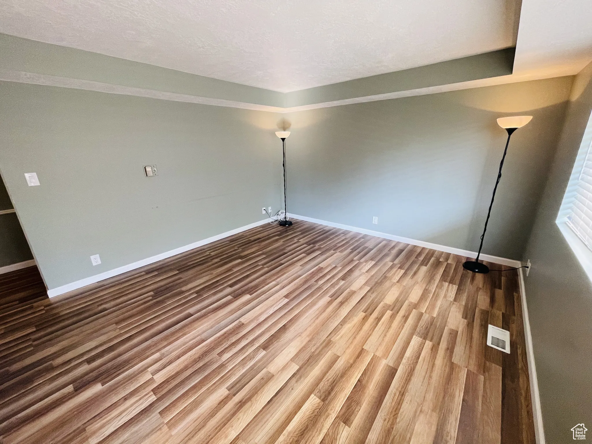Unfurnished room featuring baseboards, wood finished floors, and a textured ceiling