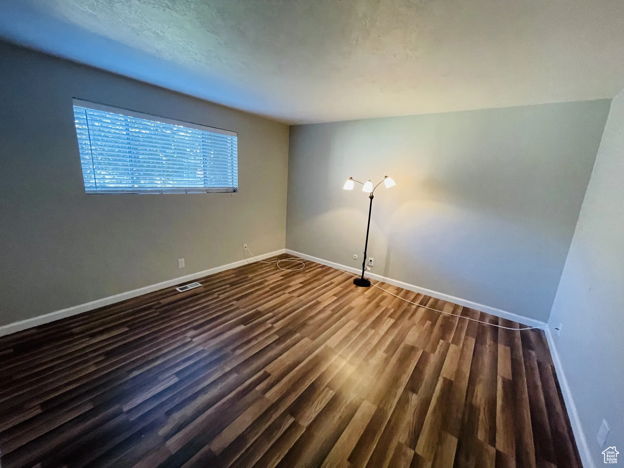 Empty room with dark wood-type flooring and baseboards