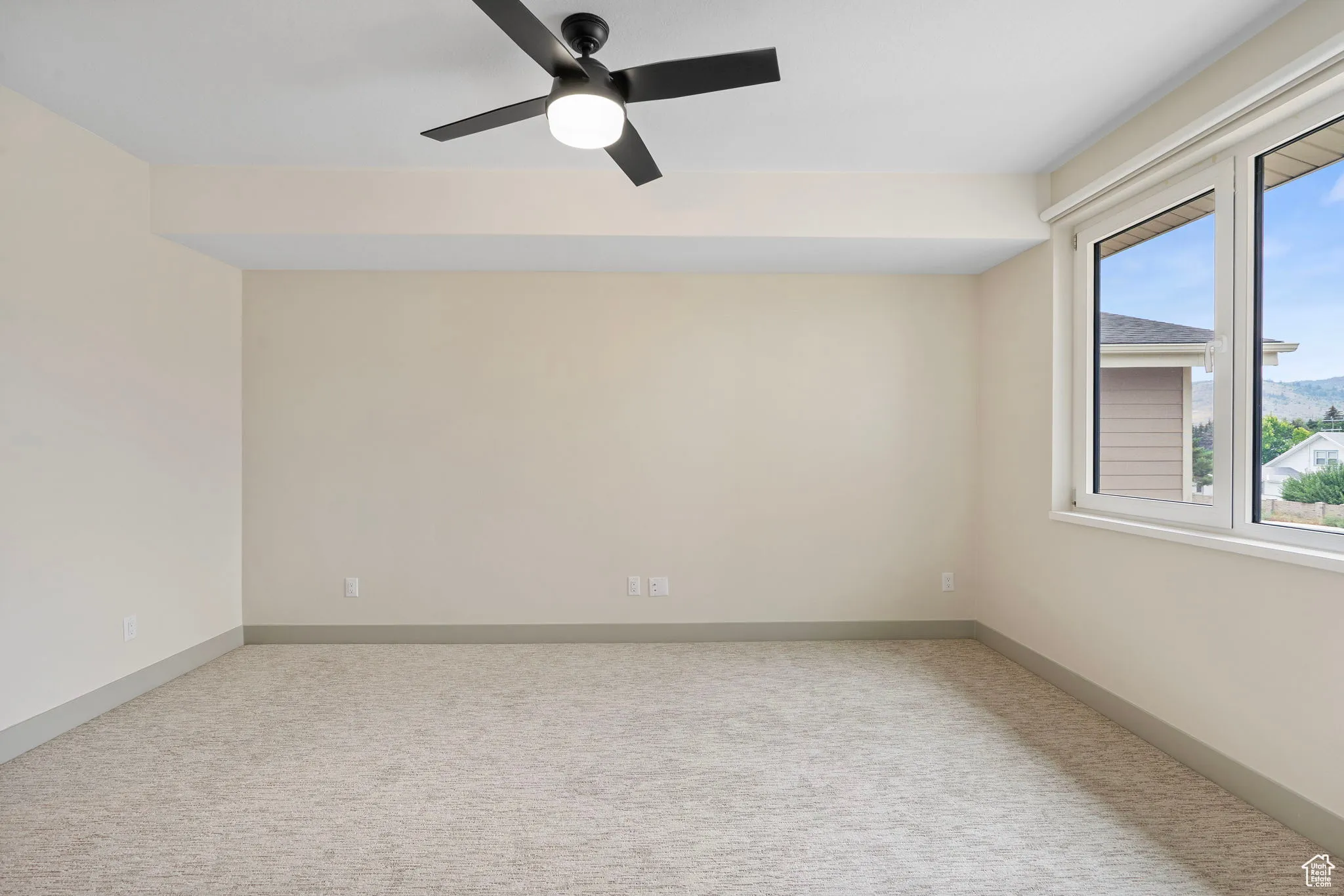 Spare room featuring light colored carpet and ceiling fan