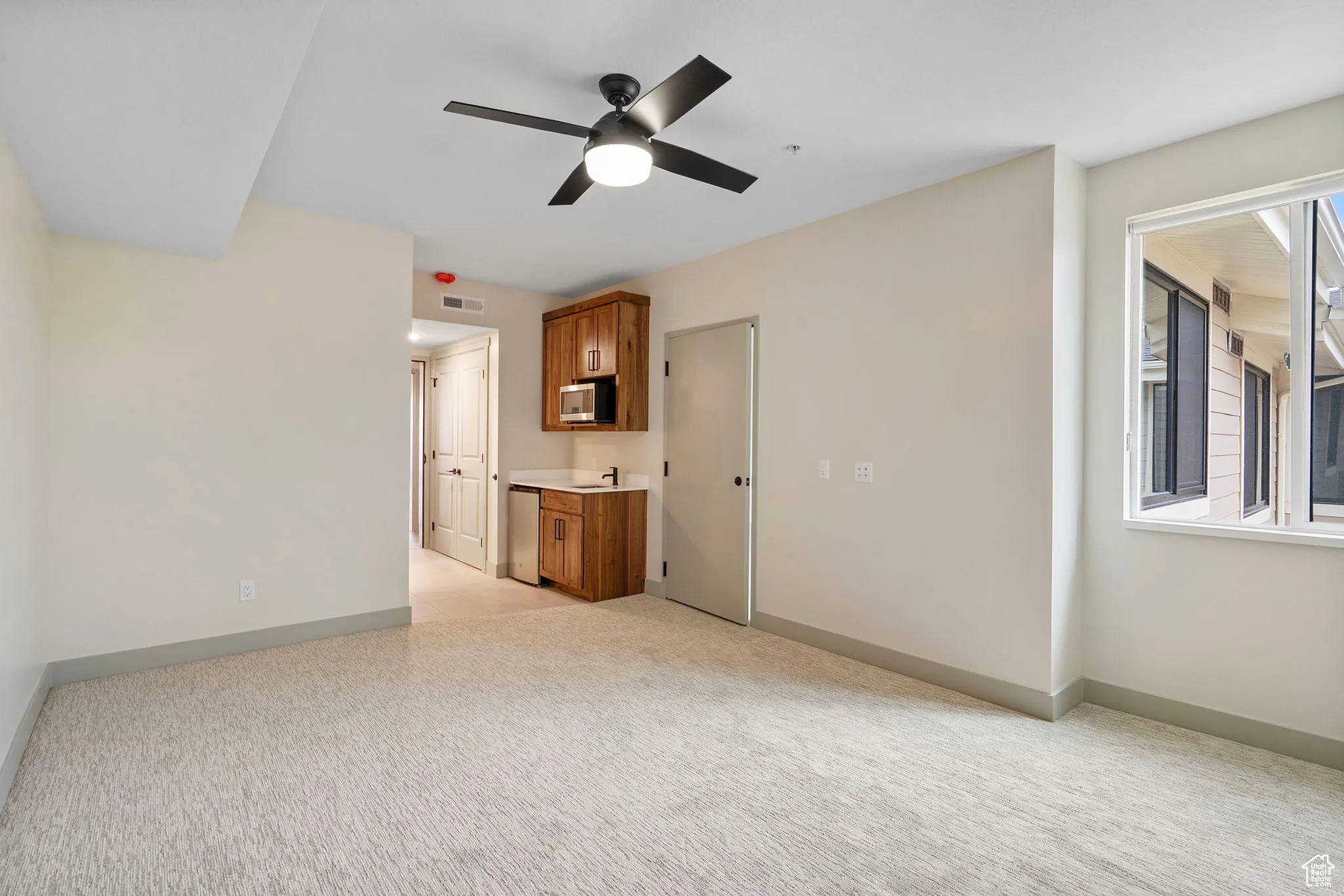 Unfurnished living room featuring light colored carpet and a ceiling fan