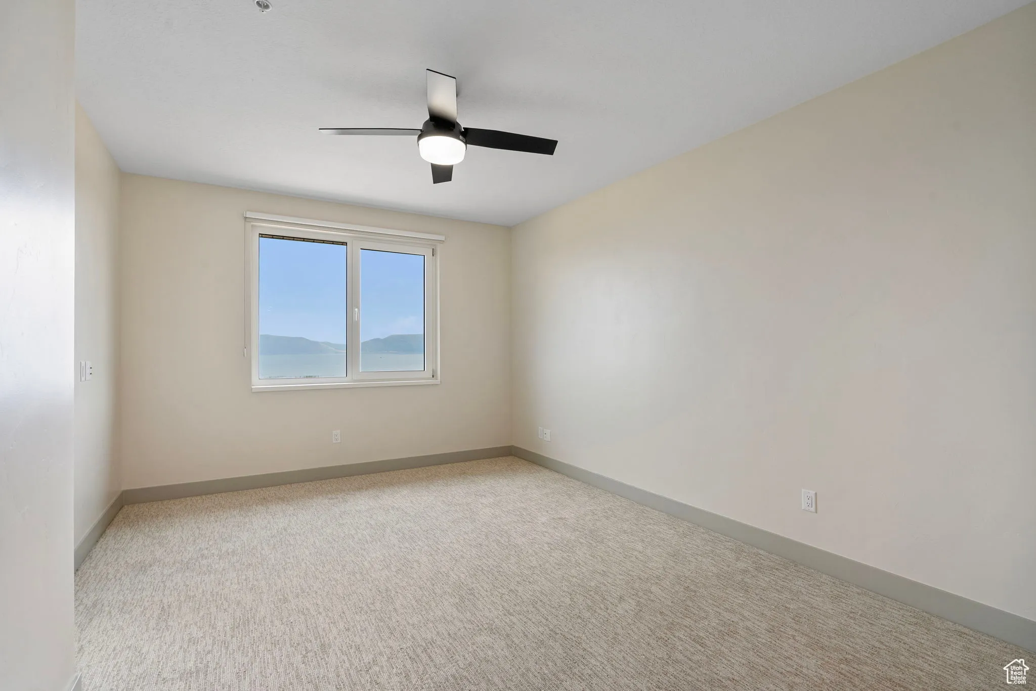 Unfurnished room with light colored carpet and ceiling fan