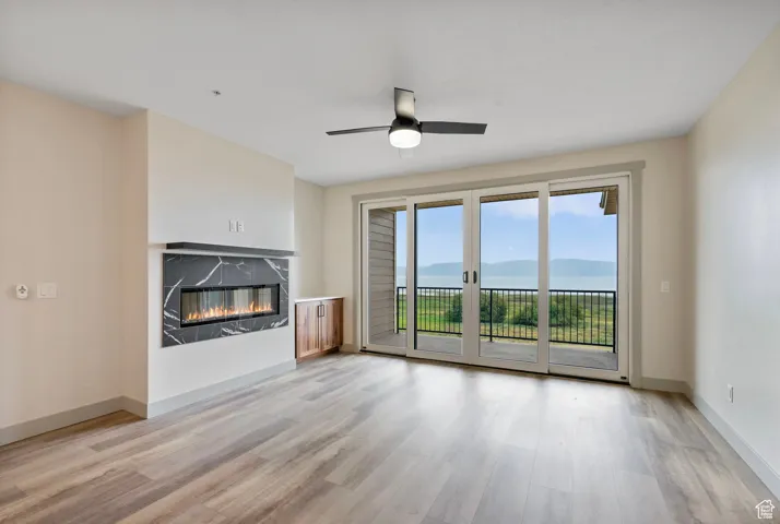 Unfurnished living room with a mountain view, a high end fireplace, light wood-type flooring, and a ceiling fan
