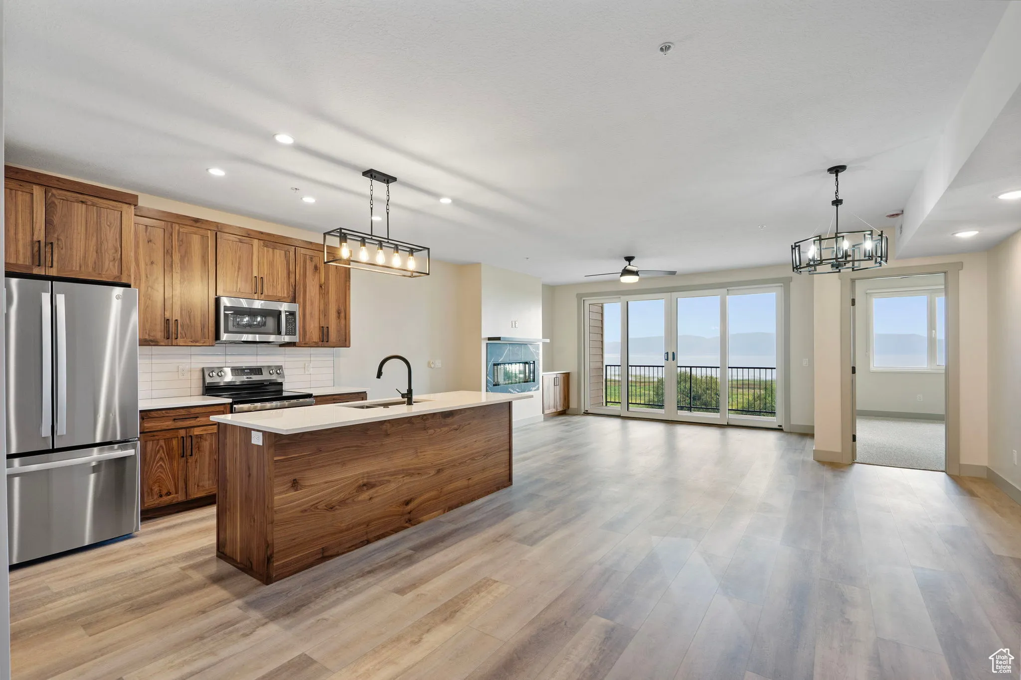 Kitchen with recessed lighting, brown cabinetry, stainless steel appliances, open floor plan, and decorative light fixtures