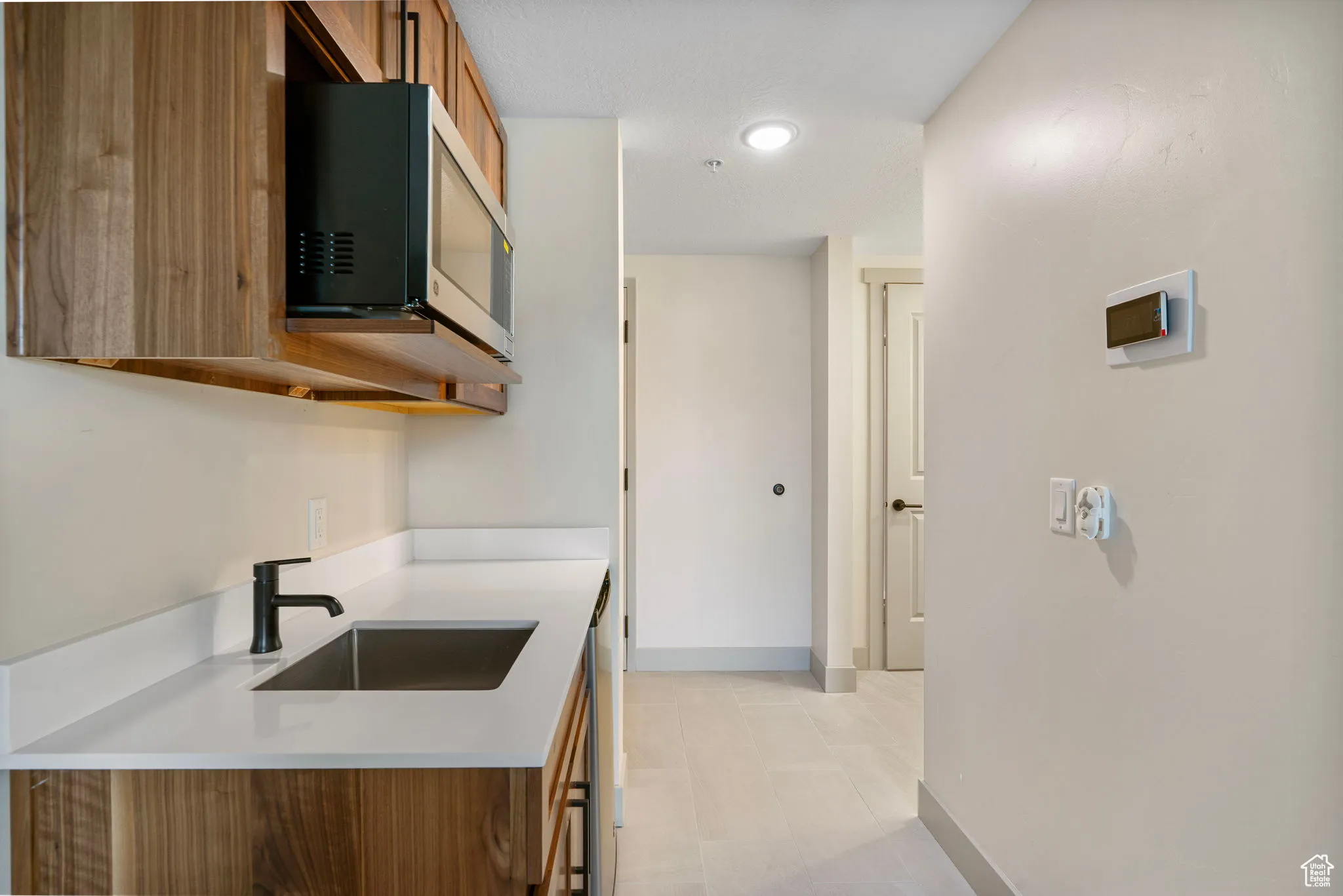 Kitchen with brown cabinets, stainless steel microwave, and light stone countertops