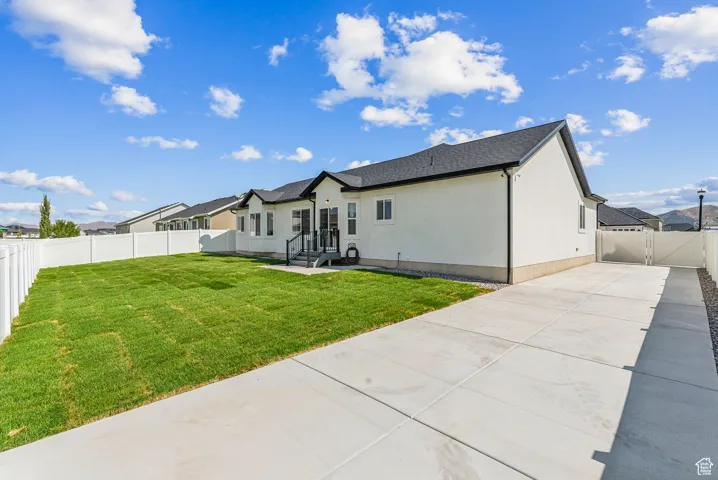 Back of property with a fenced backyard, a patio, a gate, concrete driveway, and stucco siding