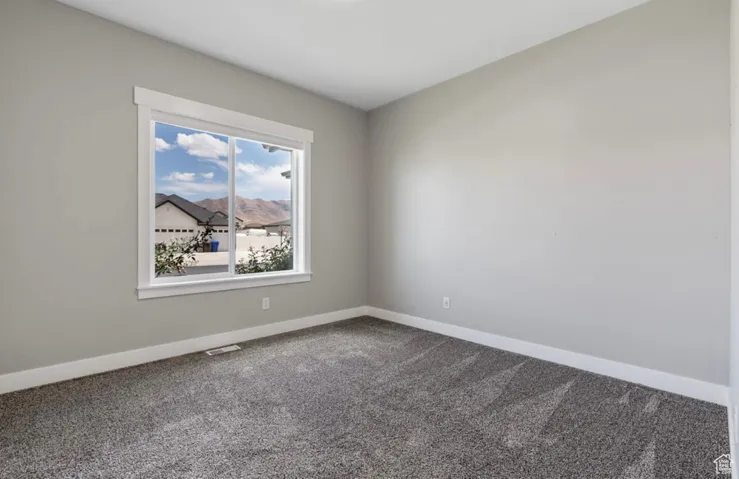 Spare room featuring dark carpet and baseboards