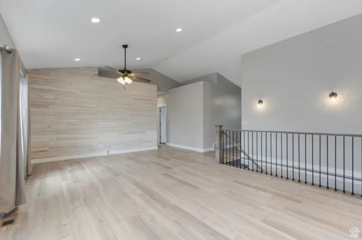 Unfurnished room featuring ceiling fan, wood finished floors, lofted ceiling, recessed lighting, and baseboards
