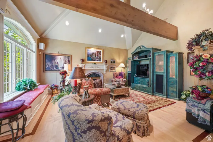 Living area with wood finished floors, a fireplace, high vaulted ceiling, beamed ceiling, and recessed lighting