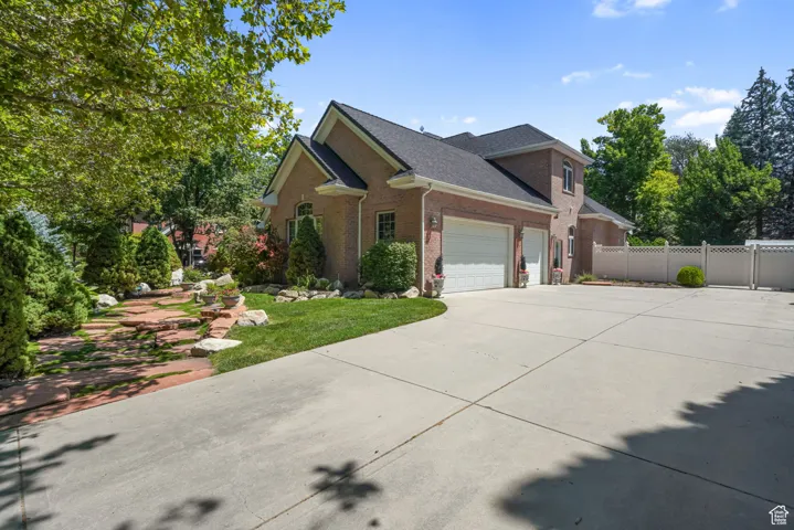 View of side of home featuring brick siding, driveway, a garage, and a shingled roof
