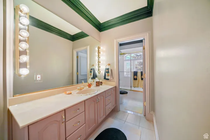 Bathroom featuring crown molding, tile patterned floors, and vanity