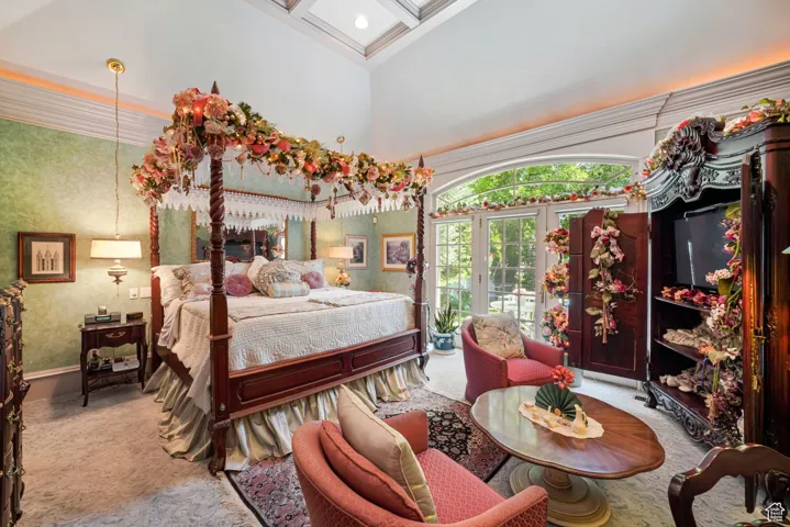 Carpeted bedroom with a high ceiling and ornamental molding