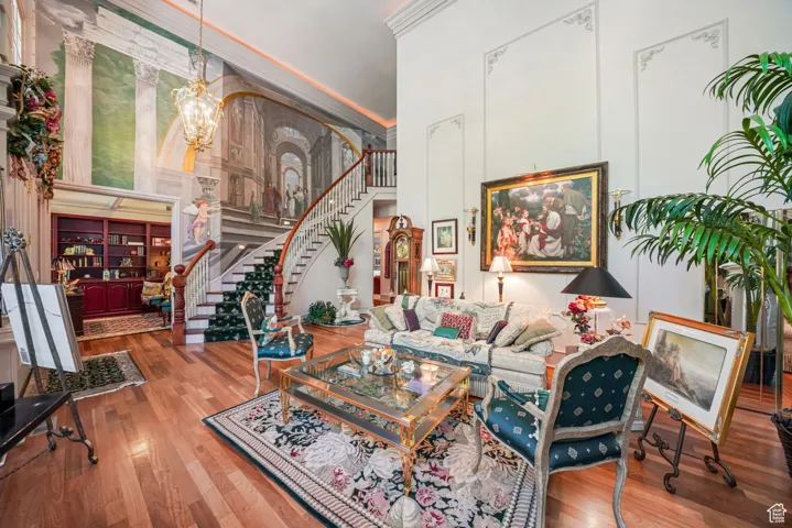 Living area with a high ceiling, stairs, wood finished floors, and a chandelier