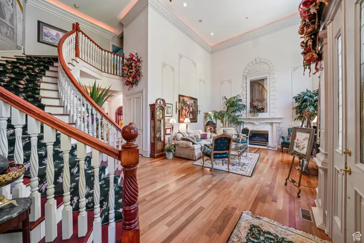 Living area with wood finished floors, stairs, ornamental molding, a towering ceiling, and a premium fireplace