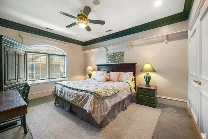 Carpeted bedroom with crown molding and ceiling fan