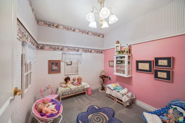 Recreation room with a chandelier, wallpapered walls, and carpet