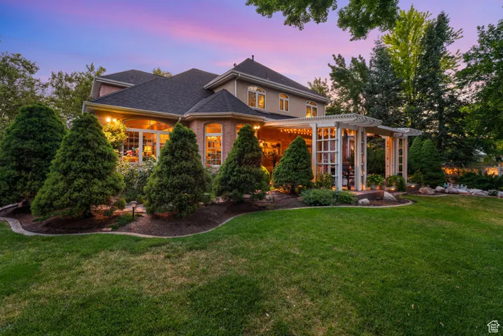 View of front facade with a pergola, a front yard, roof with shingles, and brick siding