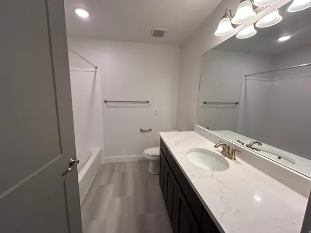 Bathroom with light wood-type flooring, vanity, shower / bath combination, and recessed lighting