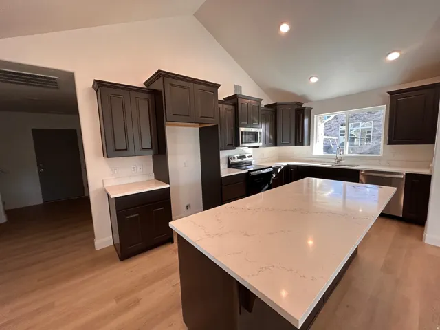 Kitchen featuring a kitchen island, appliances with stainless steel finishes, light wood-type flooring, dark brown cabinetry, and recessed lighting