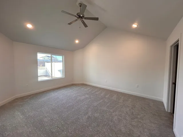Empty room with dark colored carpet, recessed lighting, high vaulted ceiling, and ceiling fan