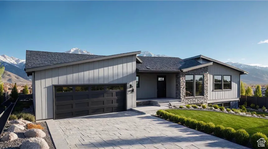 View of front of property with a mountain view, an attached garage, a front lawn, decorative driveway, and a shingled roof