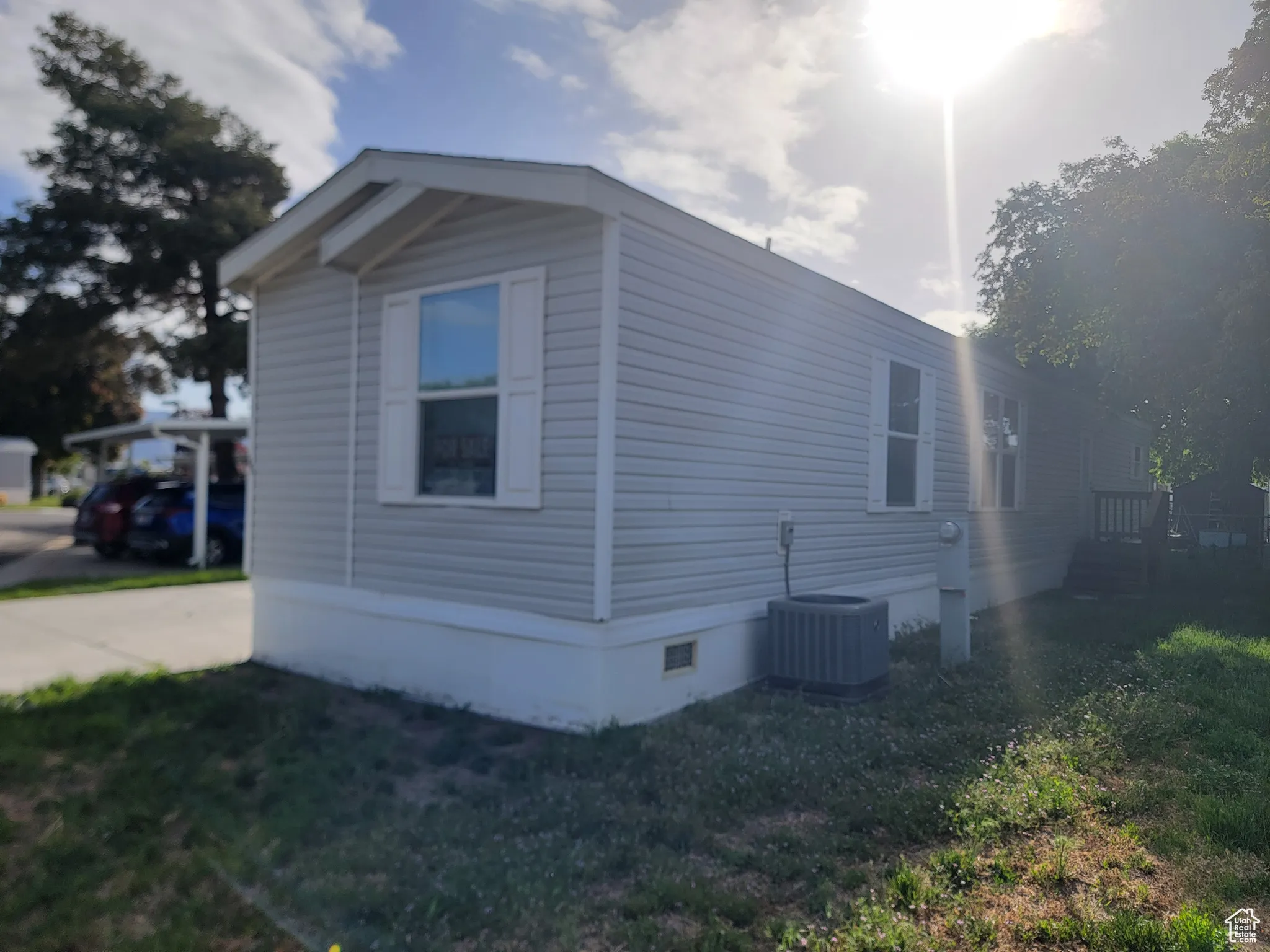 View of side of property featuring cooling unit, crawl space, and a lawn