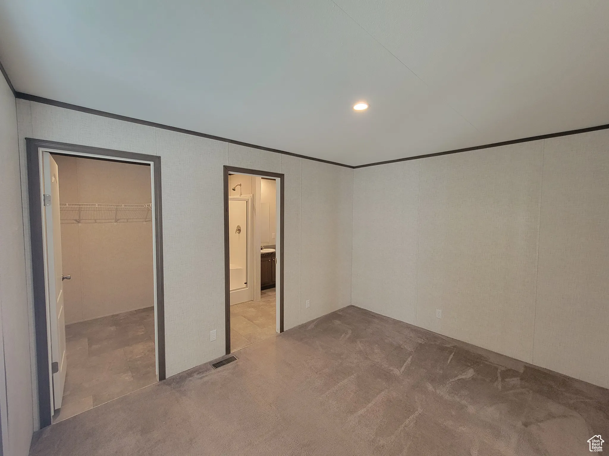 Unfurnished bedroom with crown molding, carpet floors, a spacious closet, recessed lighting, and ensuite bathroom