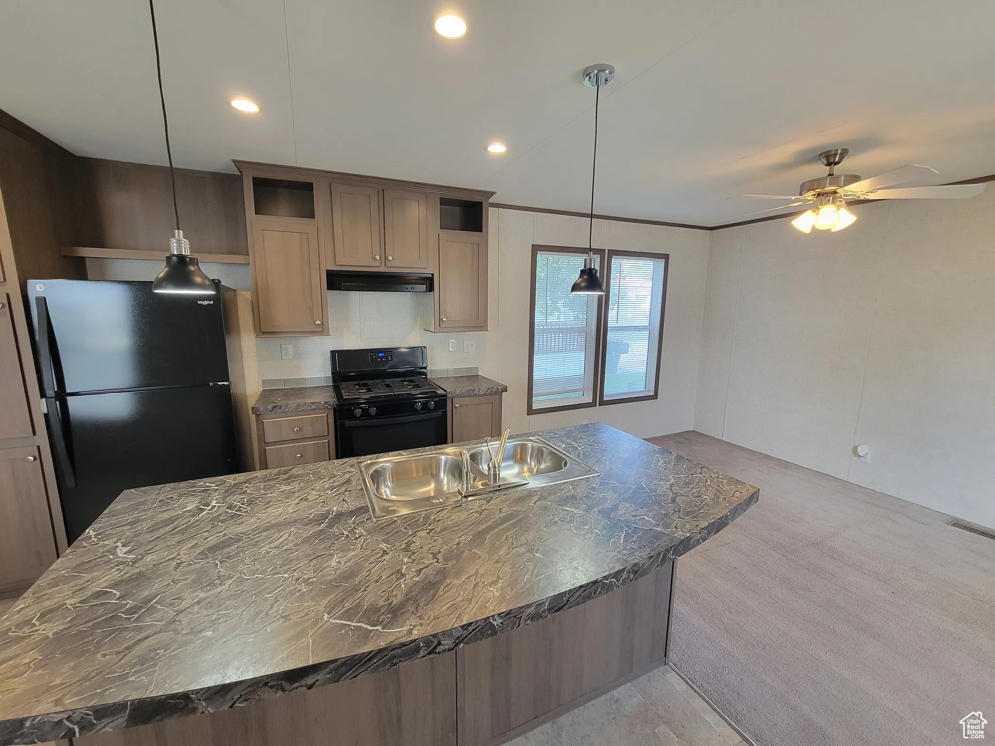 Kitchen with black appliances, under cabinet range hood, a ceiling fan, a center island, and a sink