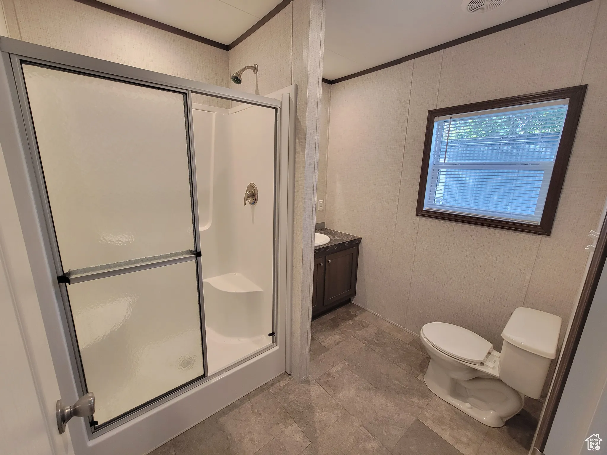 Full bath with a stall shower, toilet, ornamental molding, and vanity