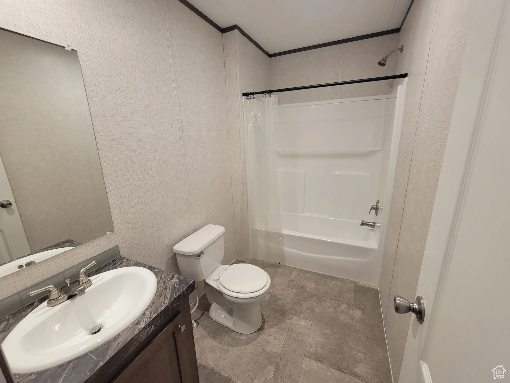 Bathroom with toilet, shower / bath combination with curtain, vanity, crown molding, and stone finish flooring