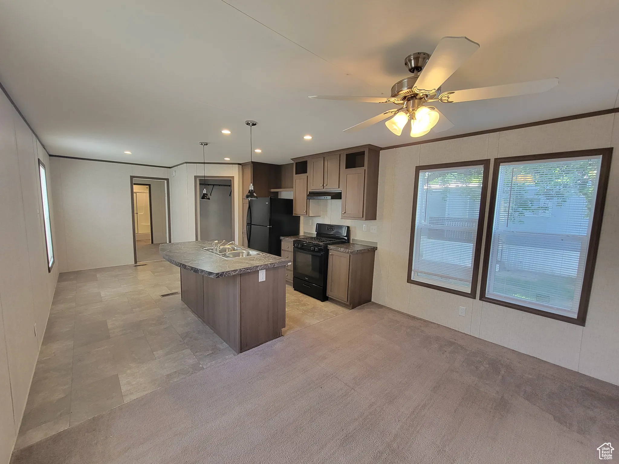 Kitchen with black appliances, plenty of natural light, a sink, a center island with sink, and recessed lighting