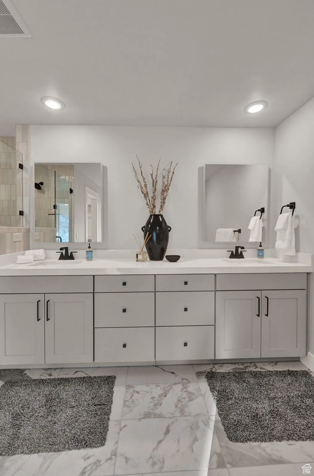 Full bathroom featuring a tile shower, double vanity, marble look tiles, and recessed lighting